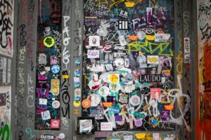 En dør dækket af farverige klistermærker og graffiti med forskellige mønstre og farver, der giver et urbant og kunstnerisk udtryk.