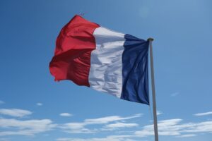 Fransk flag blafrer mod en klar blå himmel med spredte skyer i baggrunden